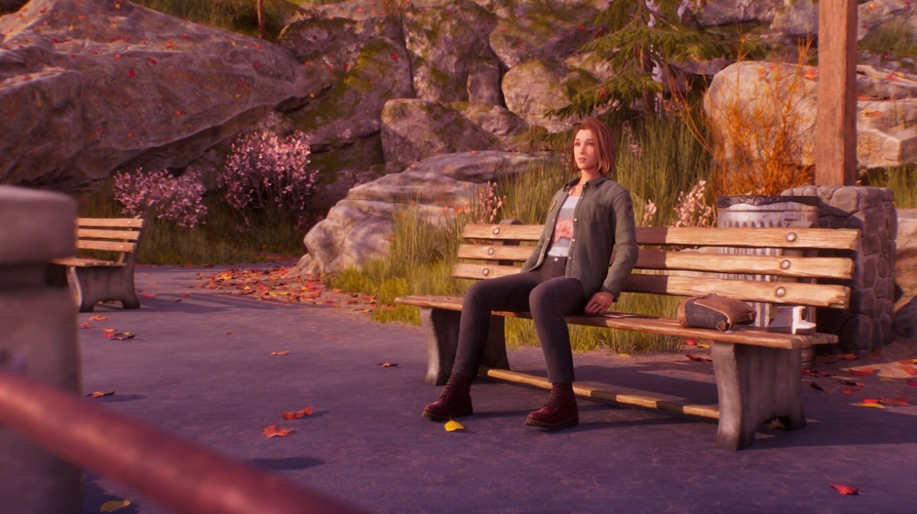 A girl sitting alone on a park bench in an autumn setting with rocks and fallen leaves around